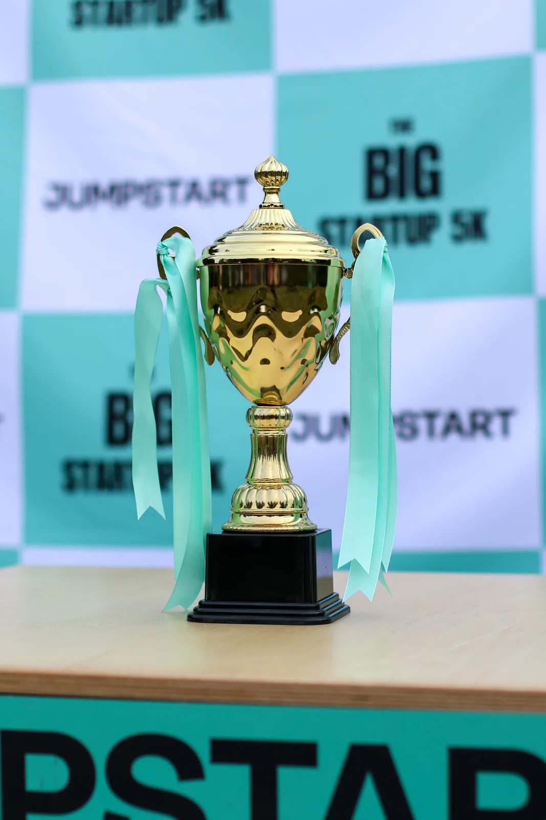 The Big Jumpstart 5K trophy on the branded backdrop